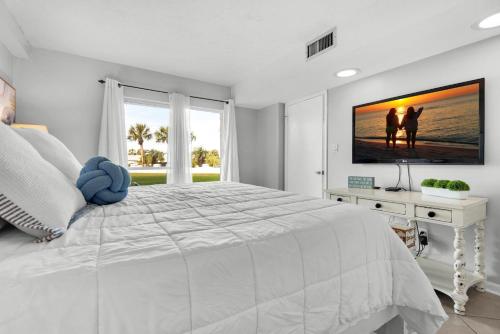 a white bedroom with a large bed and a tv at El Matador 513 in Fort Walton Beach