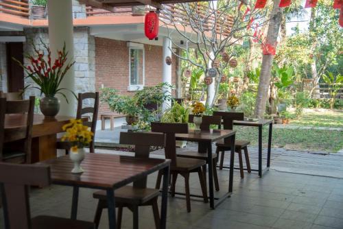a restaurant with wooden tables and chairs and plants at Laoxao RiverStone Villa in Hoi An