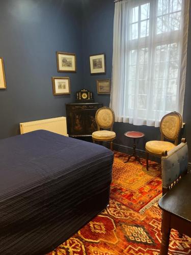 a bedroom with a bed and two chairs and a window at Queens Court Hotel in Exeter