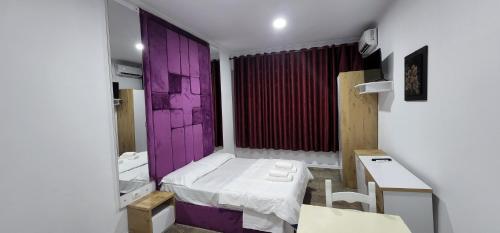 a small room with a purple door and a bed at Hotel Kleo in Rinas