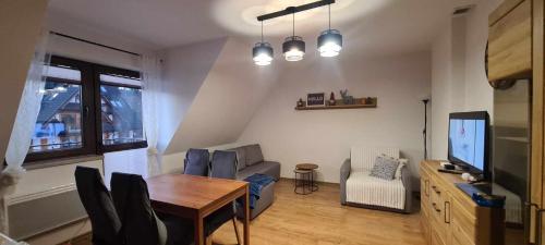 a living room with a dining table and a television at APARTAMENT z kuchnia Białka Tatrzańska in Białka Tatrzanska