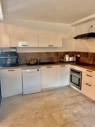 a large kitchen with white cabinets and appliances at Domaine du Reginu in Santa-Reparata-di-Balagna