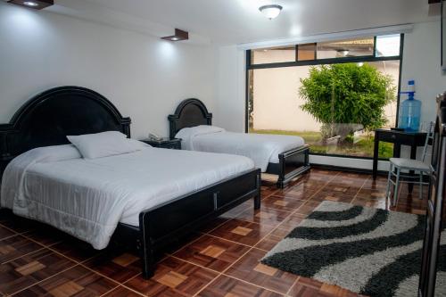 a bedroom with two beds and a window at Hostería El Prado in Ibarra