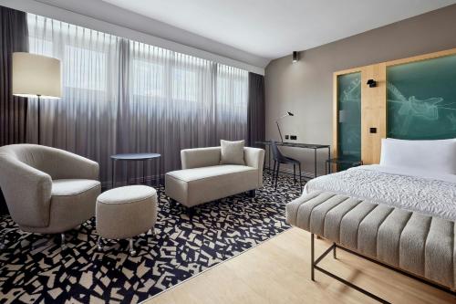 a hotel room with a bed and chairs and a desk at Le Méridien Vienna in Vienna