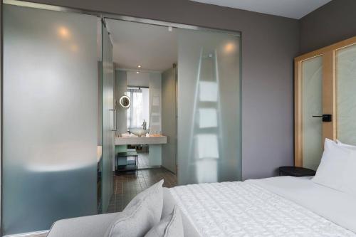 a bedroom with a white bed and a bathroom at Le Méridien Vienna in Vienna