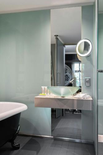 a bathroom with a sink and a tub and a mirror at Le Méridien Vienna in Vienna