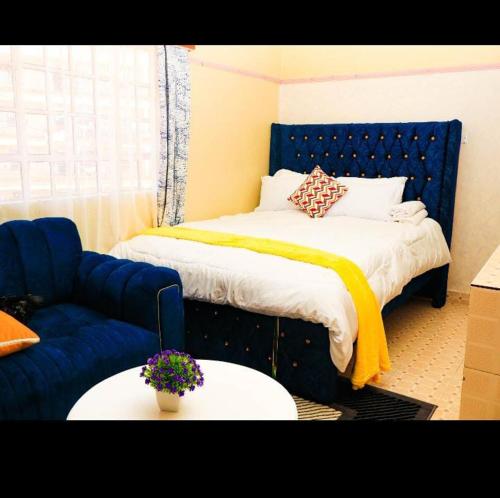 a bedroom with a blue bed and a blue couch at Cozy Homes in Thika
