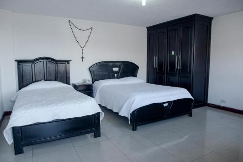 a bedroom with two beds and a black cabinet at Hostería El Prado in Ibarra