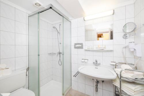 a white bathroom with a shower and a sink at Aparthotel Landhaus St. Joseph (Indoor Pool) in Mayrhofen