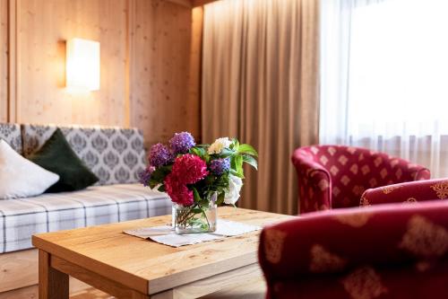 a living room with a vase of flowers on a table at Aparthotel Landhaus St. Joseph (Indoor Pool) in Mayrhofen