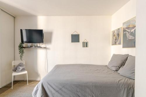 une chambre avec un lit et une télévision à écran plat dans l'établissement Studio Lumière in Lyon, à Lyon
