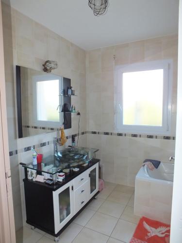 une salle de bain avec un lavabo, une baignoire et un miroir dans l'établissement Maison Familiale à St-Brevin - Confort & Sérénité, à Saint-Brévin-les-Pins