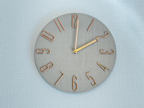 a metal clock on a wall with roman numerals at Serene Highness in Dazaifu
