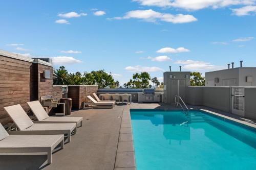 a rooftop patio with a swimming pool and lounge chairs at Carnelian Calm-Pool BBQ Rooftop Walk to the Beach in Los Angeles