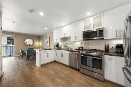 a kitchen with white cabinets and appliances and a table at Carnelian Calm-Pool BBQ Rooftop Walk to the Beach in Los Angeles