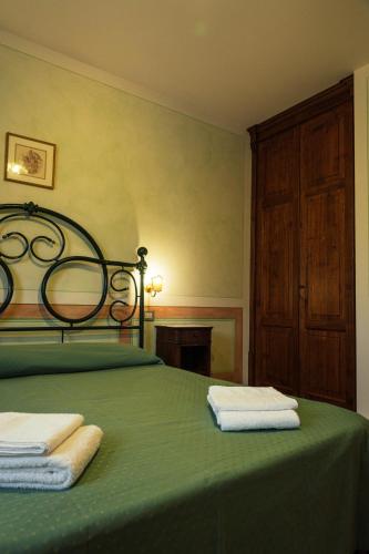 a bedroom with a green bed with towels on it at Agriturismo Casal Gheriglio in Lucignano