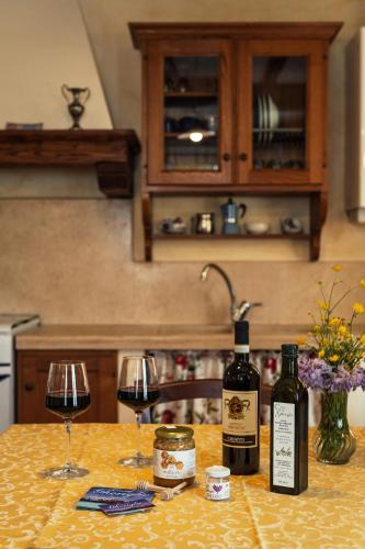 two bottles of wine and two glasses on a kitchen counter at Agriturismo Casal Gheriglio in Lucignano
