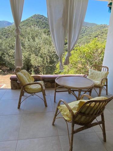 un patio con 2 sillas, una mesa y una ventana en Vue spectaculaire sur la baie de Budoni, en Tamarispa