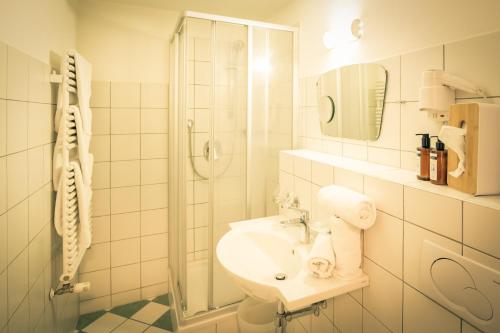 a white bathroom with a shower and a sink at Posthotel Lechtal, Arlberg in Holzgau