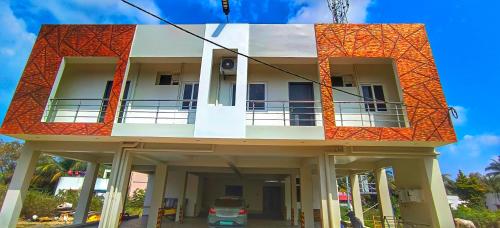 a building with an orange roof with a car parked in front at Shivalaya's 2BHK Service Apartment Near Adiyogi & Siruvani in Alāndurai