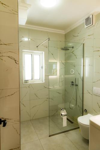 a bathroom with a glass shower with a toilet and a sink at Hotel Univers Laç in Fushë-Milot