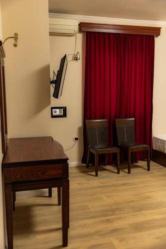 a room with two chairs and a red curtain at Hotel Univers Laç in Fushë-Milot