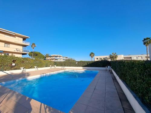 a swimming pool with blue water in front of a building at Charmant 3 pièces vue mer in Antibes