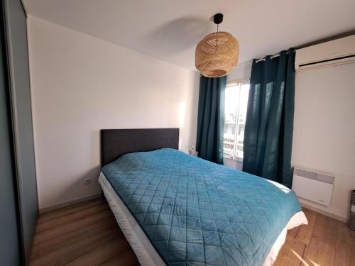 a bedroom with a bed with a blue comforter at Charmant 3 pièces vue mer in Antibes