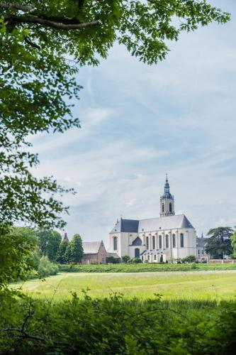 a large white building with a tower on a field at B&B de ZIL in Herselt