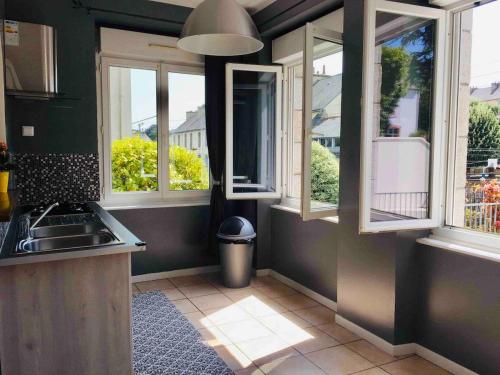 - une cuisine avec 3 fenêtres et un évier dans l'établissement Spacieux appartement terrasse au coeur de la ville, à Quimperlé