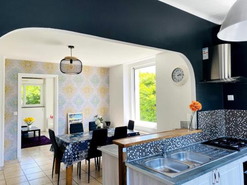 une cuisine avec un évier et une table avec des chaises dans l'établissement Spacieux appartement terrasse au coeur de la ville, à Quimperlé