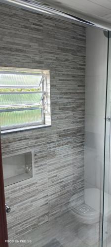 a bathroom with a glass shower with a window at Chalés Vitória in Cunha