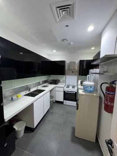 a kitchen with white cabinets and a sink and a refrigerator at برج داماك الكورنيش جدة - Damac Tower Corniche Jeddah in Jeddah