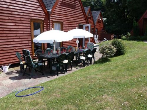 a table with chairs and umbrellas in front of a house at Chalet 68 in Kingsdown