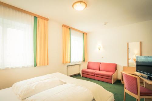 a hotel room with a bed and a red chair at Posthotel Lechtal, Arlberg in Holzgau