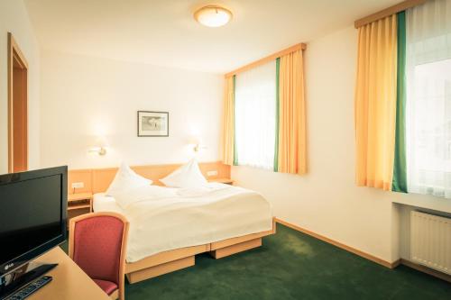 a bedroom with a bed and a desk and a tv at Posthotel Lechtal, Arlberg in Holzgau