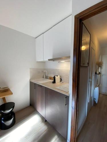 Elle comprend une petite cuisine avec des placards blancs et un réfrigérateur. dans l'établissement Sublime studio avec terrasse, à La Colmiane