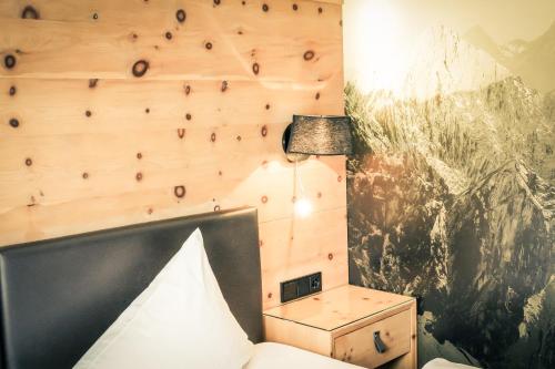 a bedroom with a wooden wall with a lamp and a bed at Posthotel Lechtal, Arlberg in Holzgau