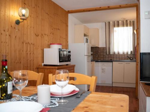 une cuisine et une salle à manger avec une table et des verres à vin dans l'établissement Chalet Mitoyen 3 Pièces 6 Pers. avec Terrasse et Piscine - Résidence Le Hameau du Puy, Dévoluy - FR-1-504-483, à Superdevoluy
