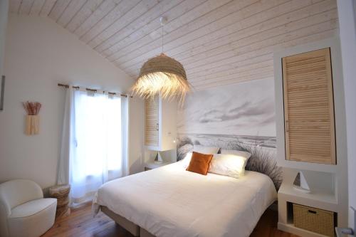 - une chambre avec un lit blanc et un lustre dans l'établissement Lou Mae - Capbreton - Magnifique Villa à 800 m de l'Océan et à proximité du port de plaisance, à Capbreton