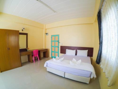 a bedroom with a large white bed and a desk at Wansiri Mansion in Songkhla