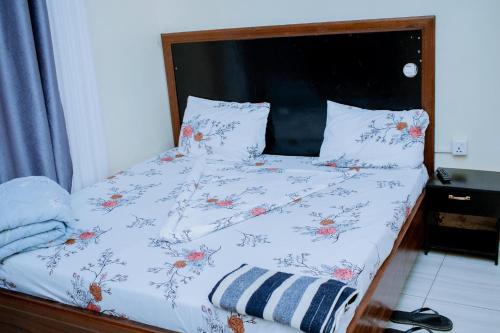 a bed with a white comforter with flowers on it at BC Empire Luxury Guest House in Kigali