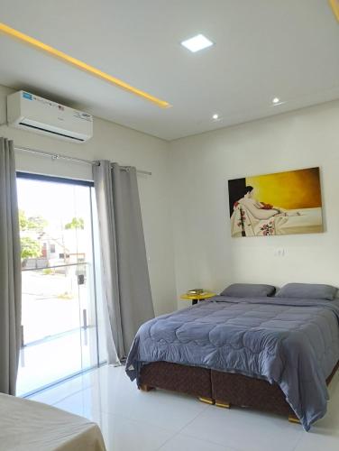 a bedroom with a bed and a large window at Casa Amarte - Sobrado Privado com Garagem in Guaíra