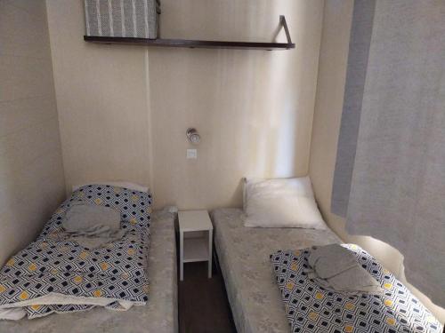 - 2 lits dans une petite chambre avec une petite table dans l'établissement Claude et chris536, à La Roque-dʼAnthéron