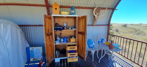 a room with a balcony with a table and shelves at Dopper Joris Bruidswa Adam se Uitspanning in Orania