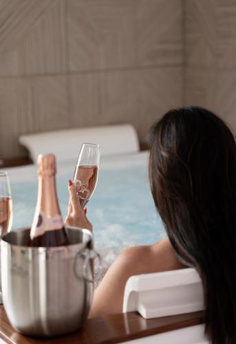 a woman sitting in a bath tub with a glass of wine at L'OLYMPE DES SENS in Portiragnes