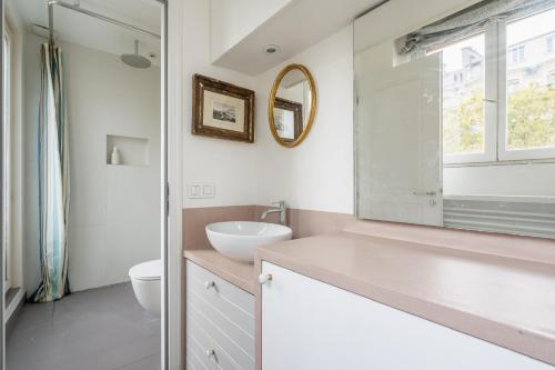 une salle de bain avec un lavabo et un miroir dans l'établissement Bel appartement cosy, emplacement idéal, à Paris