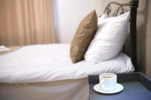 a cup of coffee on a table next to a bed at Zurabyan's Home in Yerevan