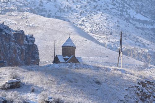a small church on a snowy hill with a mountain at Areni Lodge in Areni