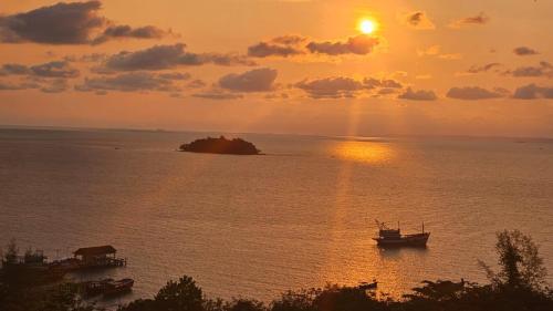 a boat in the water with a sunset in the background at Sea Views bungalow kohrong in Koh Rong Island
